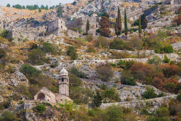 Best time to visit Kotor Montenegro hikers on the Kotor Fortress trail in early morning before cruise ship crowds arrive with dramatic Bay of Kotor view below