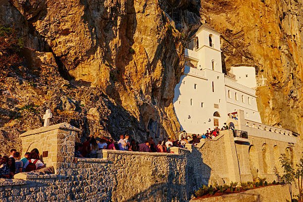 Ostrog Monastery Montenegro dramatic white Orthodox monastery built into a steep limestone cliff face at 900 metres altitude with the Zeta Valley visible far below